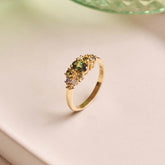 Unique handmade cluster engagement ring in 9ct yellow gold, featuring an oval green sapphire centre stone surrounded by a colourful bouquet-inspired mix of yellow, green, and blue sapphires with two natural diamonds.