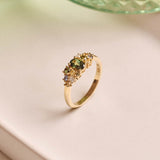 Unique handmade cluster engagement ring in 9ct yellow gold, featuring an oval green sapphire centre stone surrounded by a colourful bouquet-inspired mix of yellow, green, and blue sapphires with two natural diamonds.