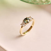Handmade 14ct yellow gold engagement ring featuring a round green sapphire centre stone flanked by two natural round diamonds; luxury heirloom-quality design perfect for weddings or special occasions.