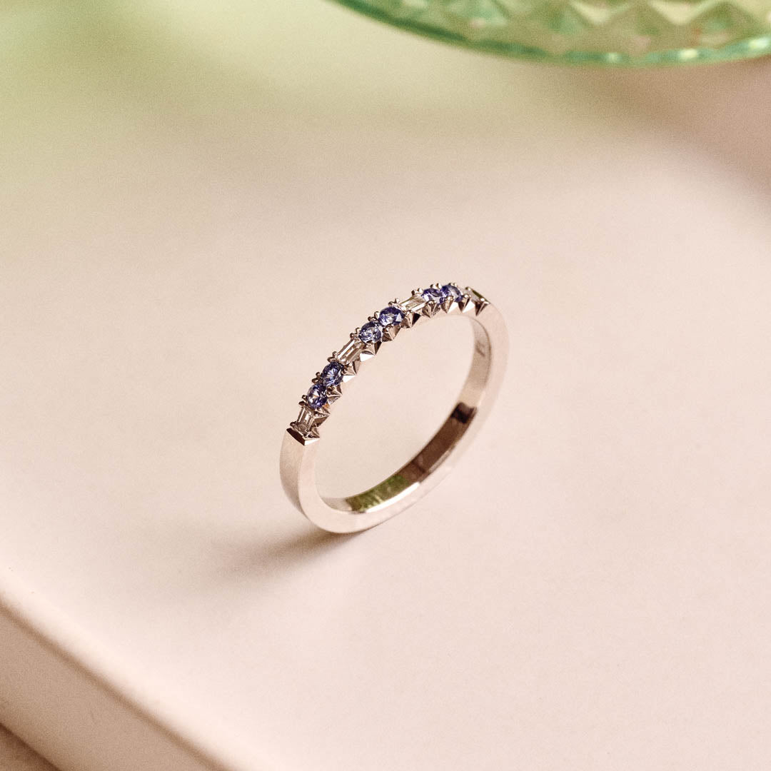 Luxury handmade platinum wedding ring featuring an intricate French pavé setting with baguette-cut natural diamonds and round light blue sapphires; a unique, high-end design perfect for weddings or milestone gifts.