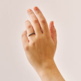 Handmade 9ct yellow gold wedding ring set with seven 2.5mm natural black diamonds; a modern, minimalist design perfect for unique wedding bands or alternative fine jewellery. Photographed on a hand with a plain background.