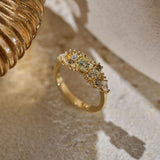 Solid gold Botanica Bouquet Ring, a cluster ring made up of a central yellow toned round natural diamond surrounded by smaller colourless, yellow and cognac diamonds photographed on an organic stone slab.