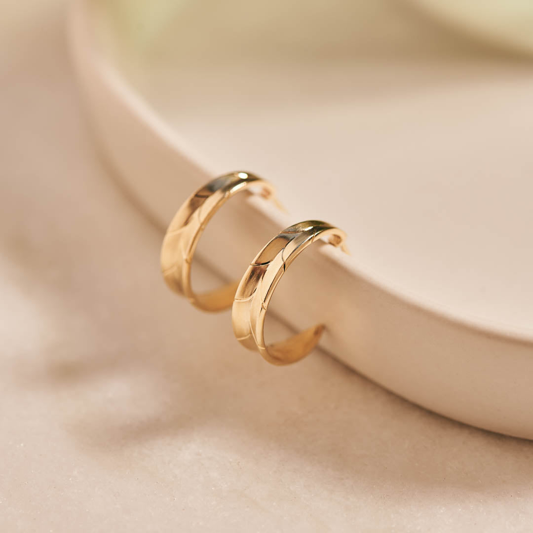 9ct yellow gold hoop earrings inspired by the shapes created by folding leaves and with engraved detailing