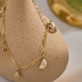 Yellow gold miniature frog, citrus wedge, lemon, pear, and leaf jewellery charms on a yellow gold paper clip chain.