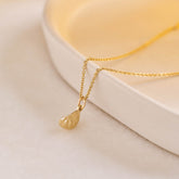 A miniature yellow gold citrus wedge jewellery charm on a yellow gold rolo chain.