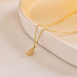 A miniature yellow gold citrus wedge jewellery charm on a yellow gold rolo chain.
