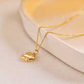 A miniature yellow gold frog jewellery charm on a yellow gold rolo chain.