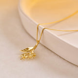 A yellow gold pendant featuring leaves and lemon blossom flowers on a yellow gold curb chain.
