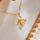 A yellow gold pendant featuring leaves and lemon blossom flowers on a yellow gold curb chain.