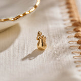 A miniature pear jewellery charm in yellow gold.