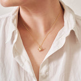 A miniature yellow gold watering can jewellery charm on a yellow gold rolo chain. Photographed being worn.