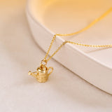 A miniature yellow gold watering can jewellery charm on a yellow gold rolo chain.