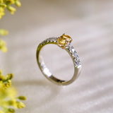 Platinum ring with central yellow sapphire set in yellow gold, and french pave natural diamonds on a blurred natural background