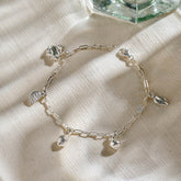 Silver miniature frog, citrus wedge, lemon, pear, and leaf jewellery charms on a silver paper clip chain.