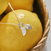 A miniature silver Lemon charm and Citrus Wedge charm on a silver rolo chain.