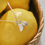 A miniature silver Lemon charm and Citrus Wedge charm on a silver rolo chain.