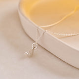 A miniature silver citrus wedge jewellery charm on a silver rolo chain.