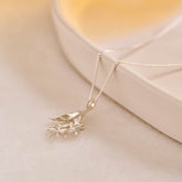 A silver pendant featuring leaves and lemon blossom flowers on a silver curb chain.