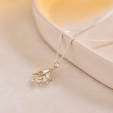 A silver pendant featuring leaves and lemon blossom flowers on a silver curb chain.