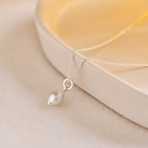 A miniature lemon jewellery charm in silver, photographed on a silver rolo chain.