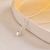 A miniature lemon jewellery charm in silver, photographed on a silver rolo chain.