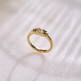 Yellow gold cluster ring set with a central natural diamond and additional blue, green, and yellow sapphires on either side. on a white background with subtle shadows.