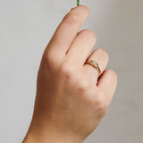 Hand wearing a Yellow gold cluster ring set with a central natural diamond and additional blue, green, and yellow sapphires on either side.