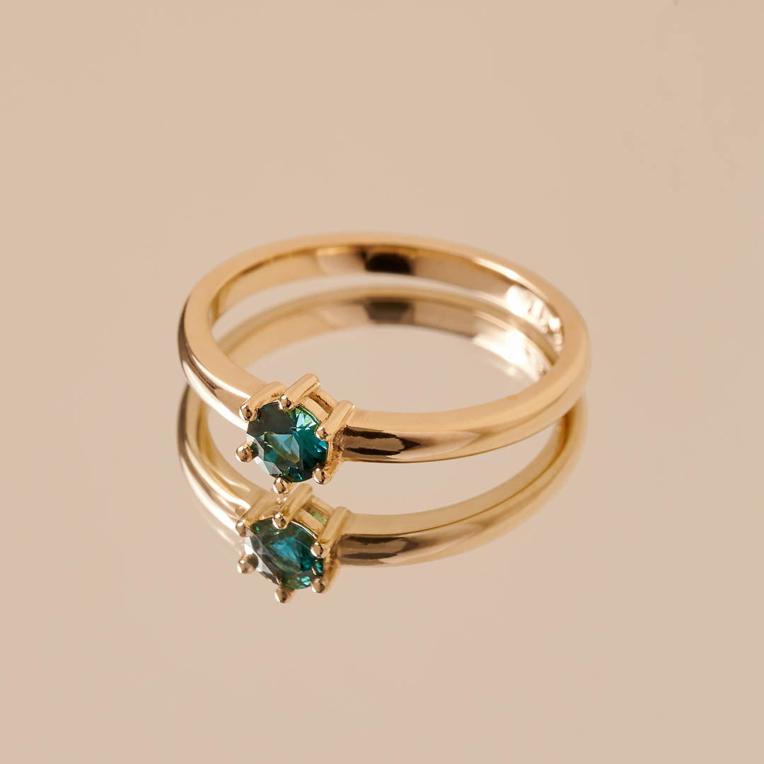 A round blue tourmaline set in a yellow gold ring