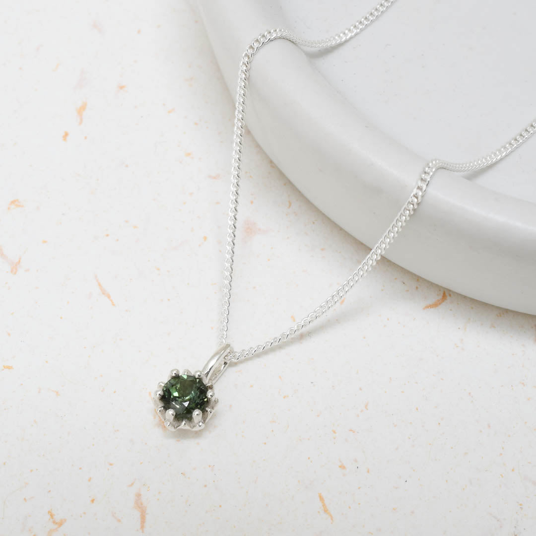 Dark green tourmaline gemstone set in a silver King Protea pendant on a silver rolo chain.