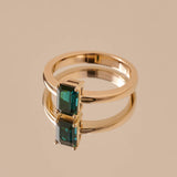 A teal rectangular cut tourmaline set in a yellow gold ring.