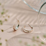 Sterling silver hoop earrings inspired by the shapes created by folding leaves with engraved detailing