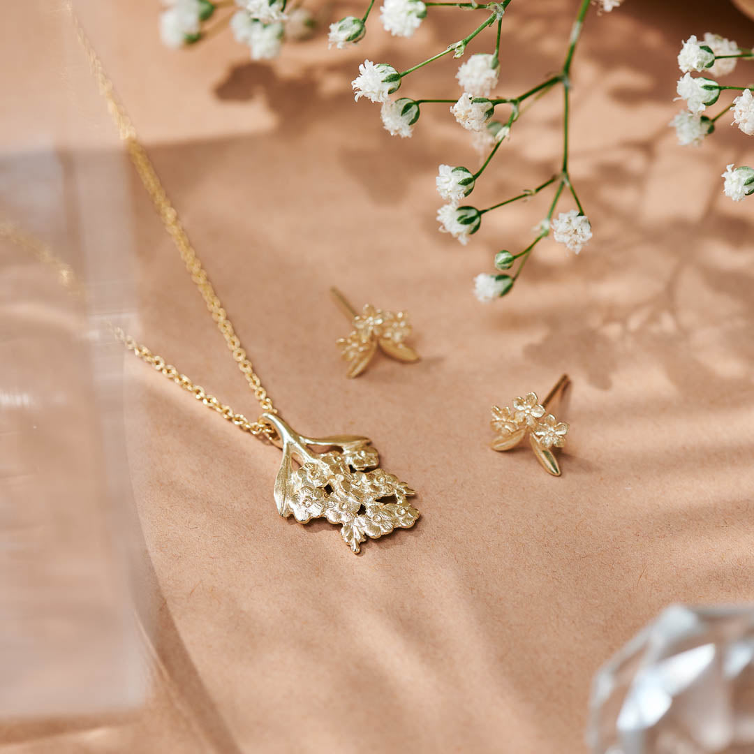 Forget-Me-Not flower inspired pendant with leaf detail, manufactured in 9ct yellow gold, and on a 9ct yellow gold rolo chain photographed with the Forget-Me-Not studs