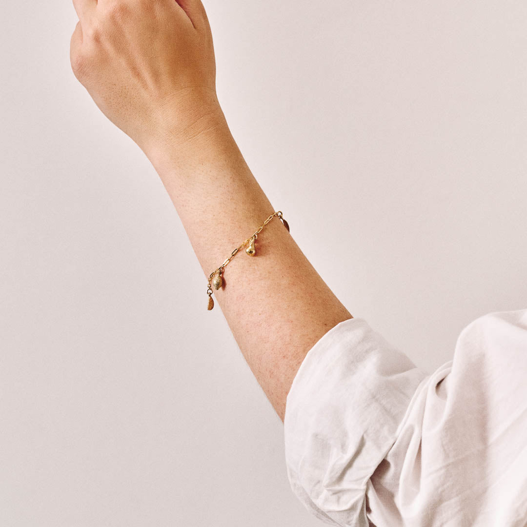 A yellow gold charm bracelet being worn