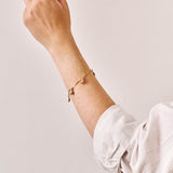 A yellow gold charm bracelet being worn