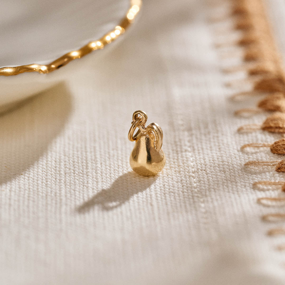 A miniature pear jewellery charm in yellow gold.
