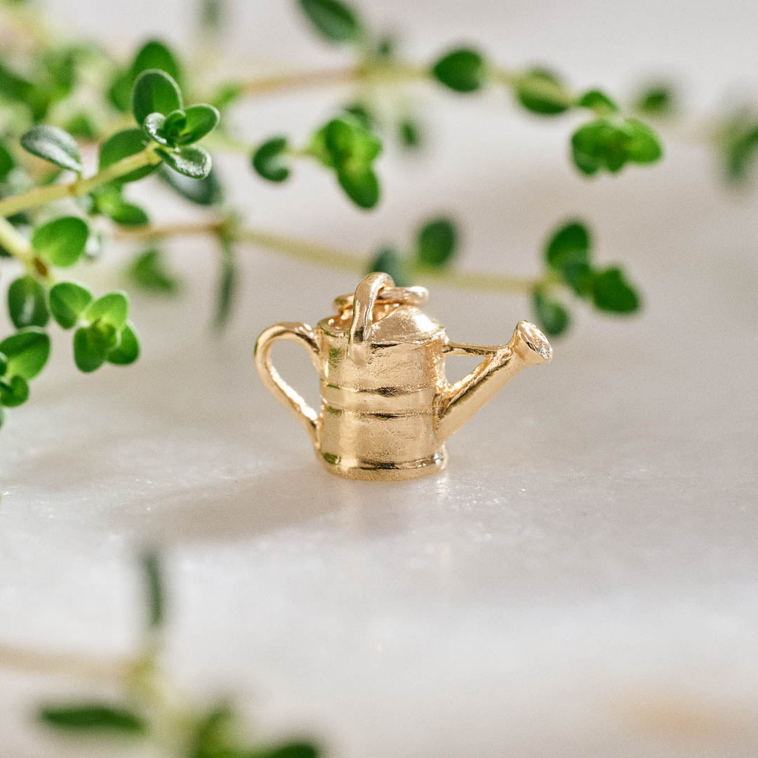 A miniature yellow gold watering can jewellery charm.