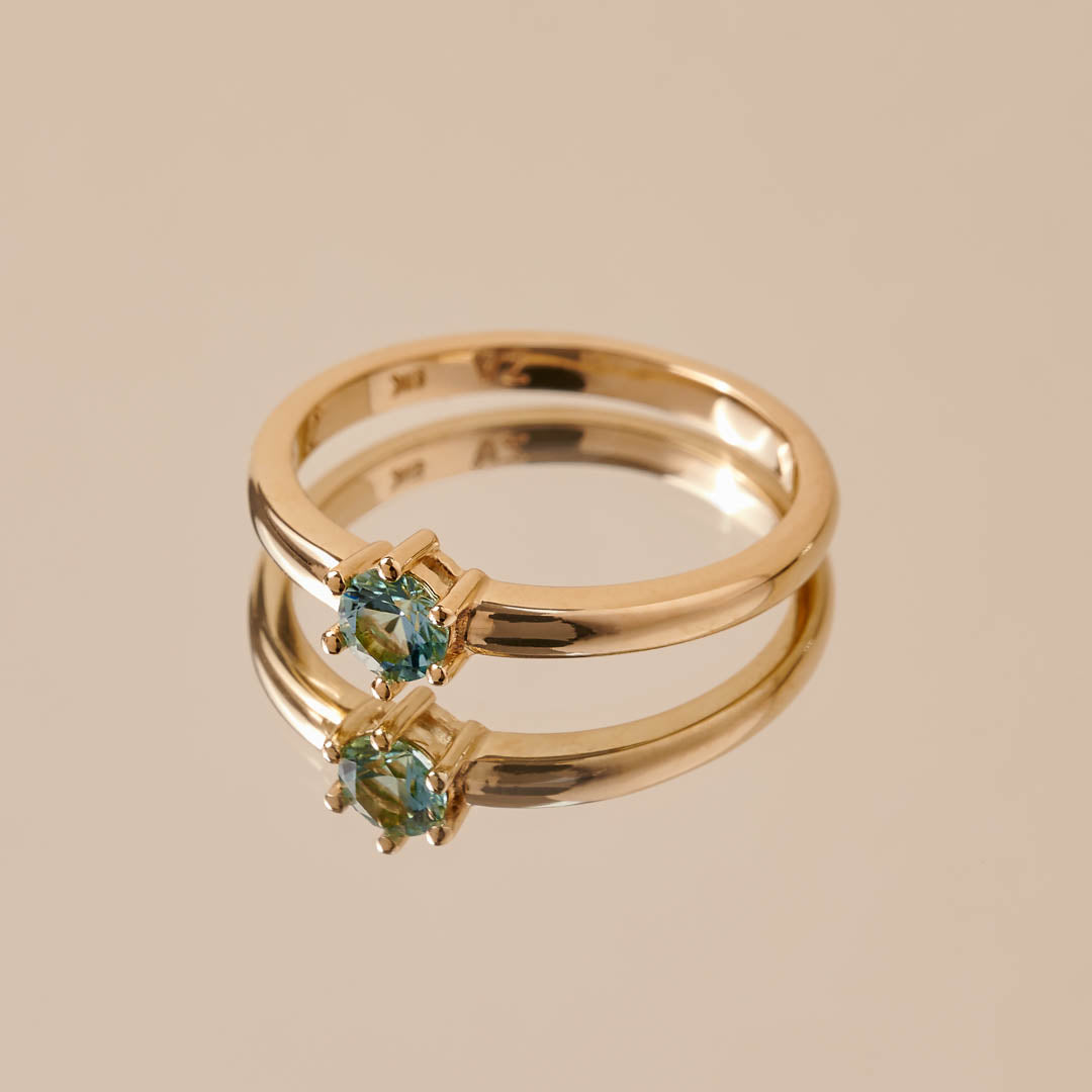 A round light blue tourmaline set in a yellow gold ring