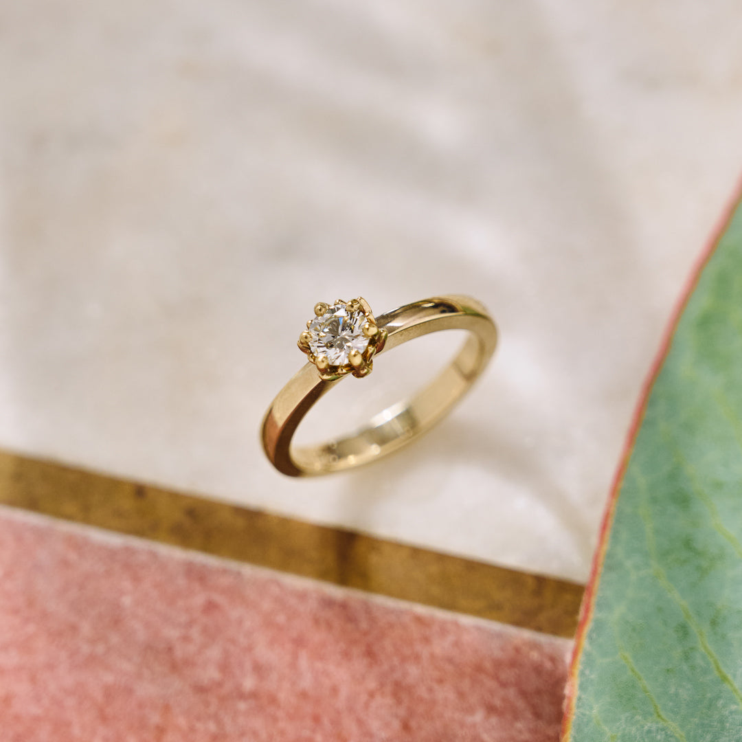 Gold ring with a diamond on a soft, blurred background