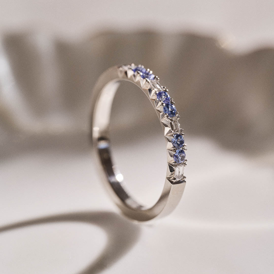 Luxury handmade platinum wedding ring featuring an intricate French pavé setting with baguette-cut natural diamonds and round light blue sapphires; a unique, high-end design perfect for weddings or milestone gifts.