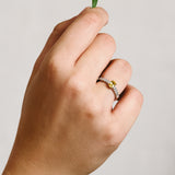 Hand wearing a platinum ring with central yellow sapphire set in yellow gold, and french pave natural diamonds.