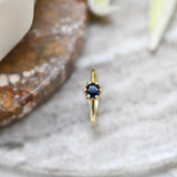 A round blue sapphire set in Botanica's iconic Protea ring manufactured in 9ct yellow gold
