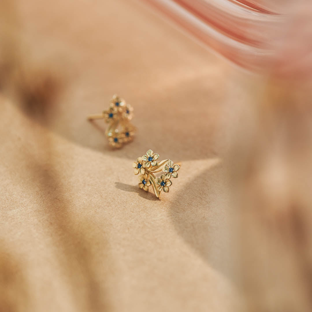 Forget-Me-Not Flower inspired studs with leaf details manufactured in 9ct yellow gold and set with light blue sapphires