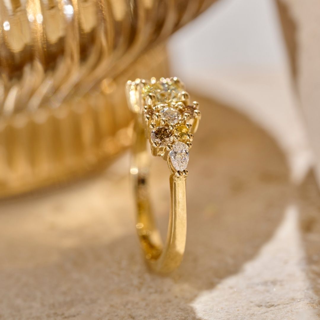 Side view of a solid gold earth-toned Bouquet Ring featuring a central yellow-toned diamond surrounded by smaller colourless and cognac diamonds, yellow sapphires and natural pear shaped diamonds. 