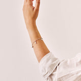 A silver charm bracelet being worn.