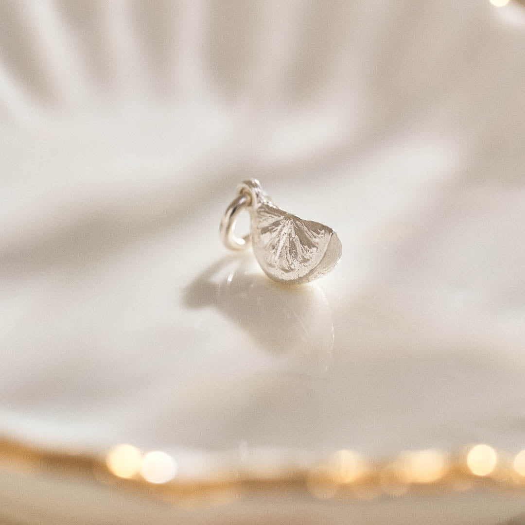 A miniature silver citrus wedge jewellery charm.
