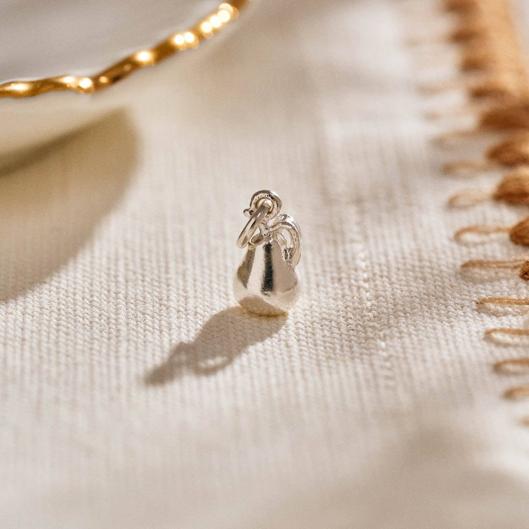 A miniature pear jewellery charm in silver.