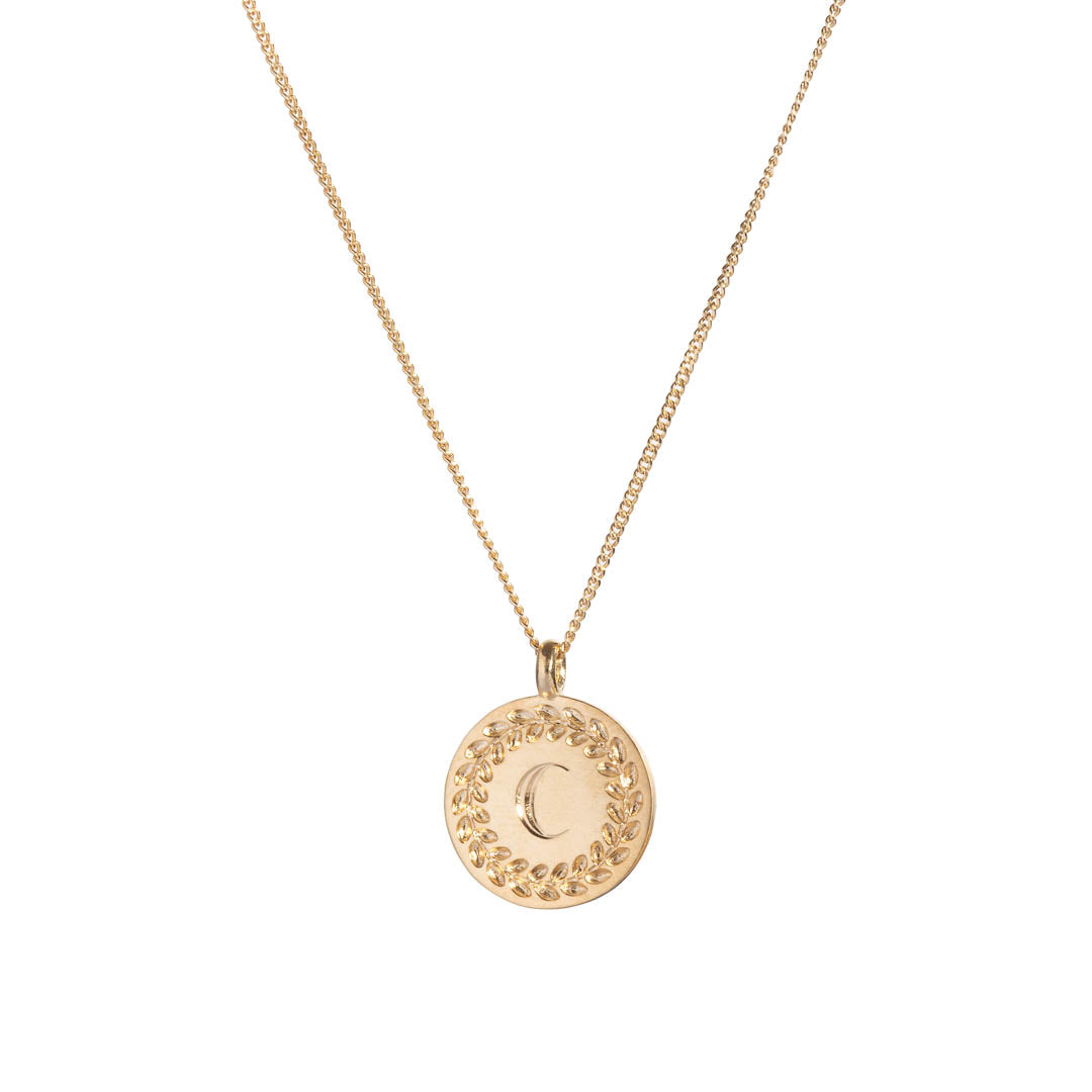 Yellow gold disc pendant with wreath border and an engraved initial.