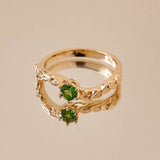 A green tourmaline ring set in a yellow gold ring with leaf detailing on the band.