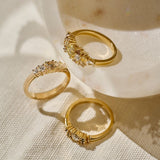 Three gold rings featuring clustered natural yellow-toned, brown and colourless diamonds photographed together on a texture tablecloth