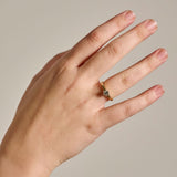 A close-up of a hand wearing the two-tone Botanica Protea Ring with a natural colourless diamond showing the fit of it on a finger, photographed against a plain light grey background.